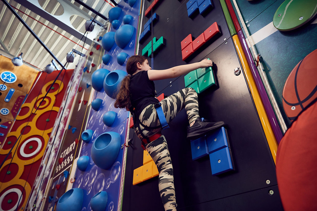 A girl climbing up the indoor climbing wall.